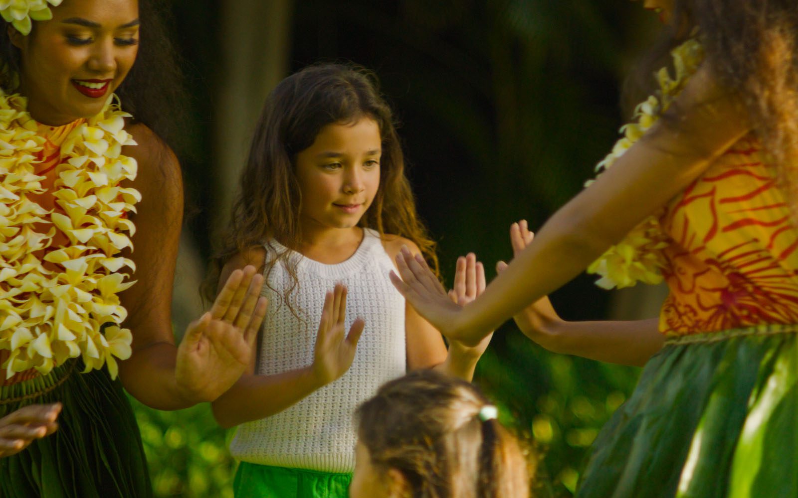 Hula Dancers and young girl enjoy learning how to hula.