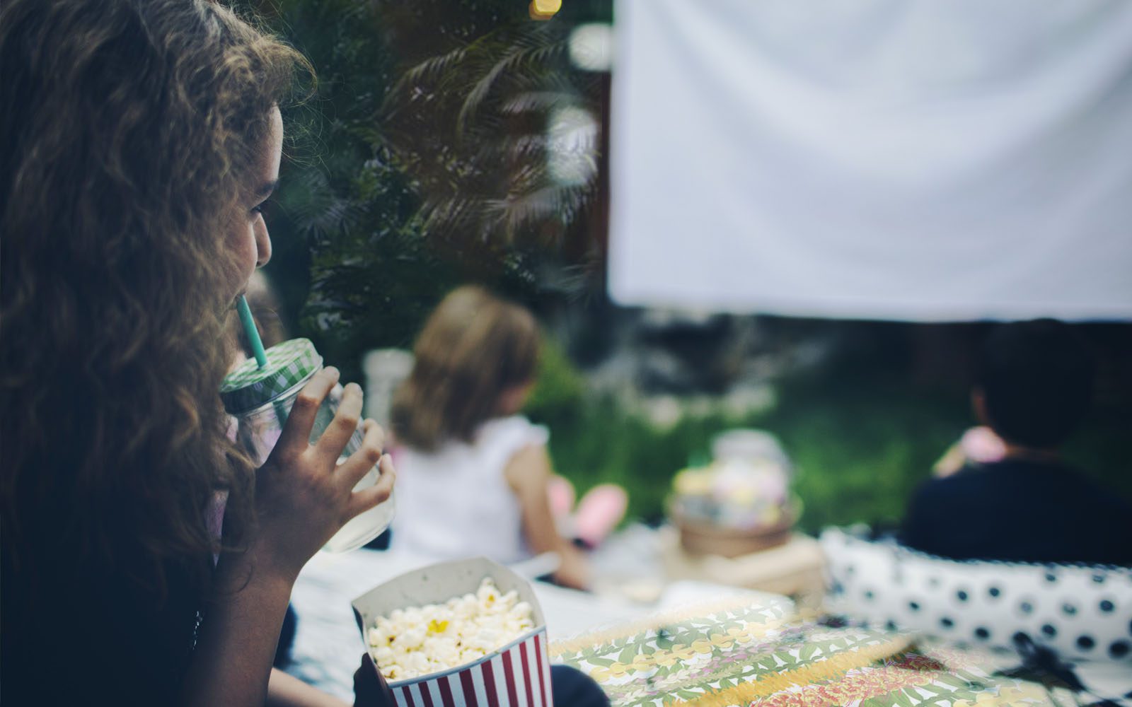 Kid watching movies on an outdoor screen on a grass lawn