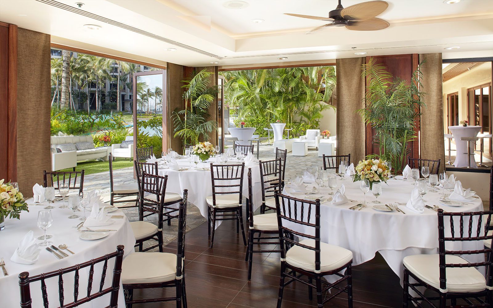 Photo of the Rainbow Suite interior showing banquet seating with round tables and patio doors open to the beautiful lagoon front.