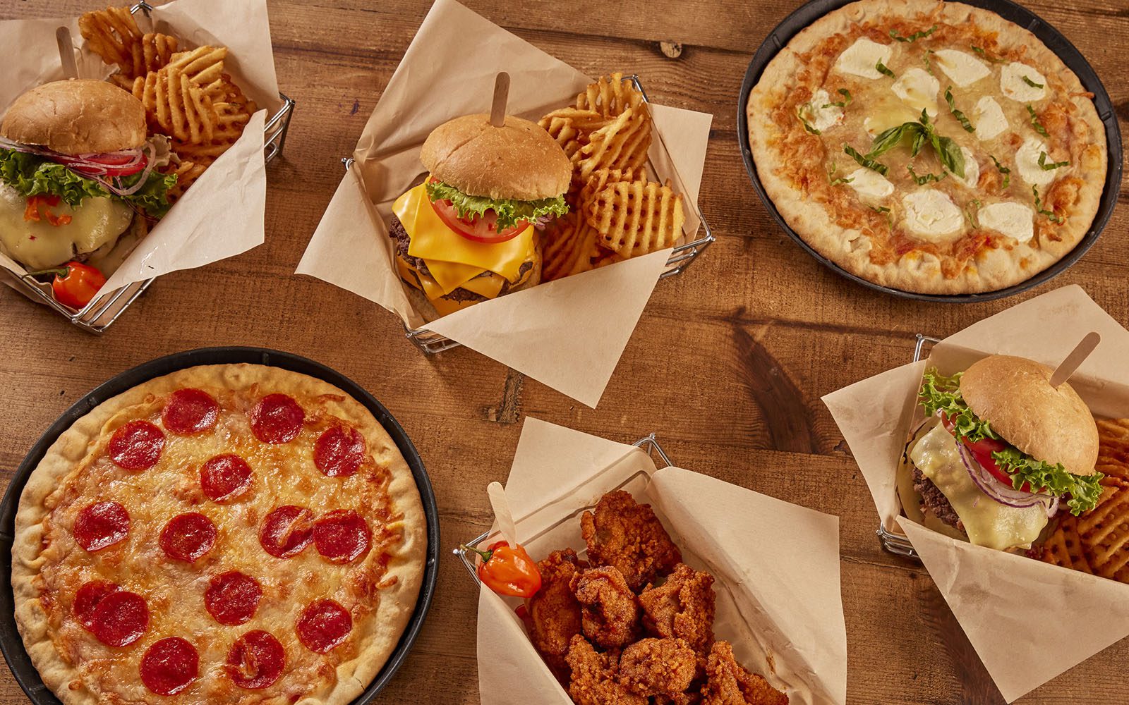 An array of food from Tropics Bar & Grill including cheeseburgers, pizza and chicken tenders.