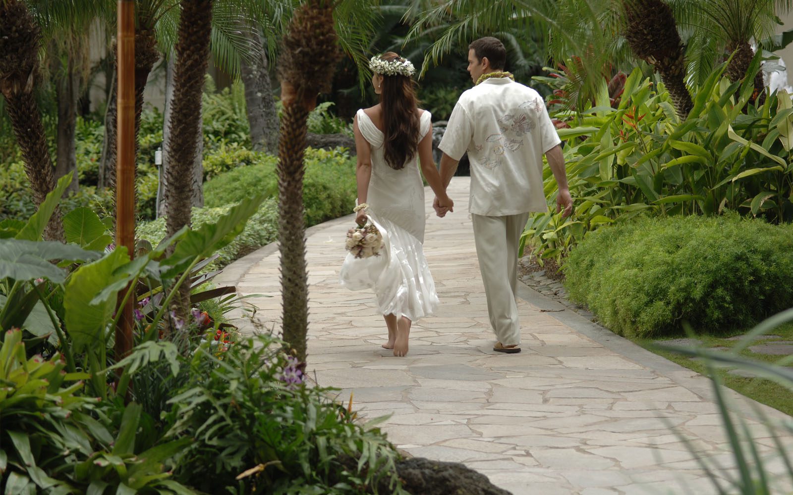 Wedding couple walking through a pathway of tropical foliage at Hilton Hawaiian Village