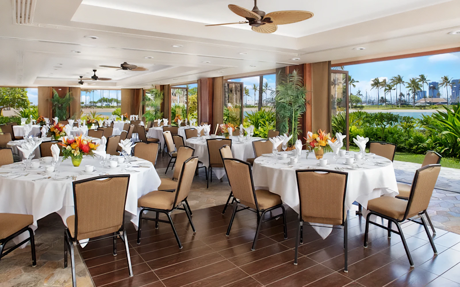 Photo of the Rainbow Suite interior showing banquet seating with round tables and patio doors open to the beautiful lagoon front.
