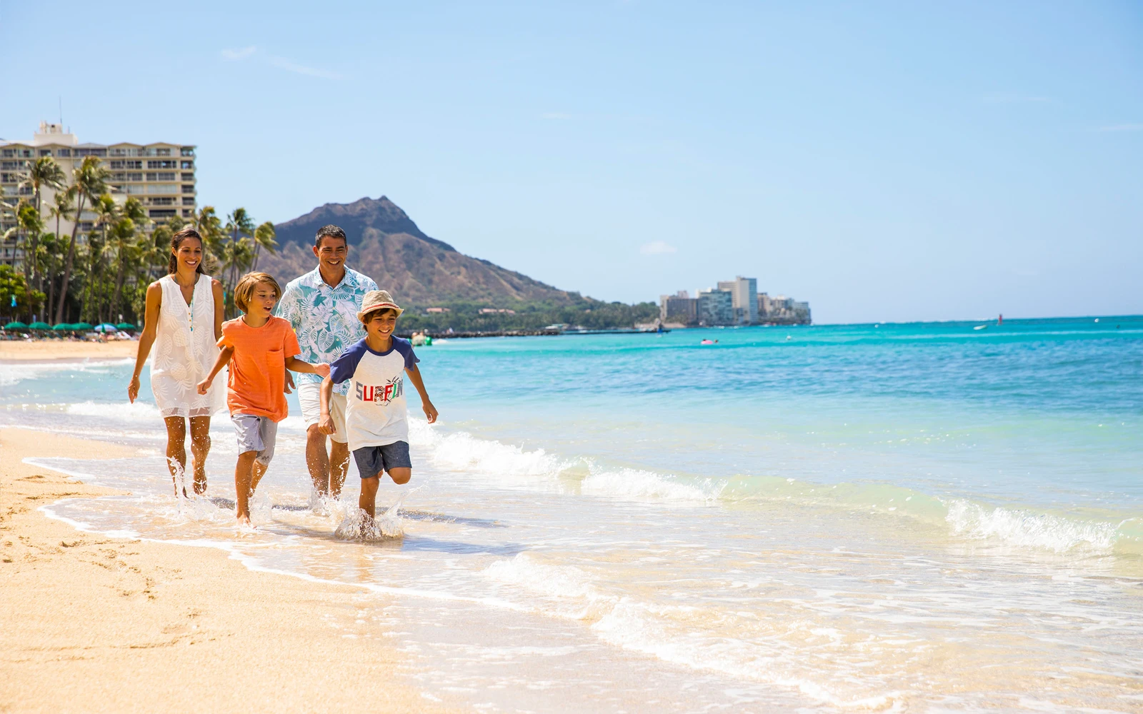 A family running on the beach at the Hilton Hawaiian Village