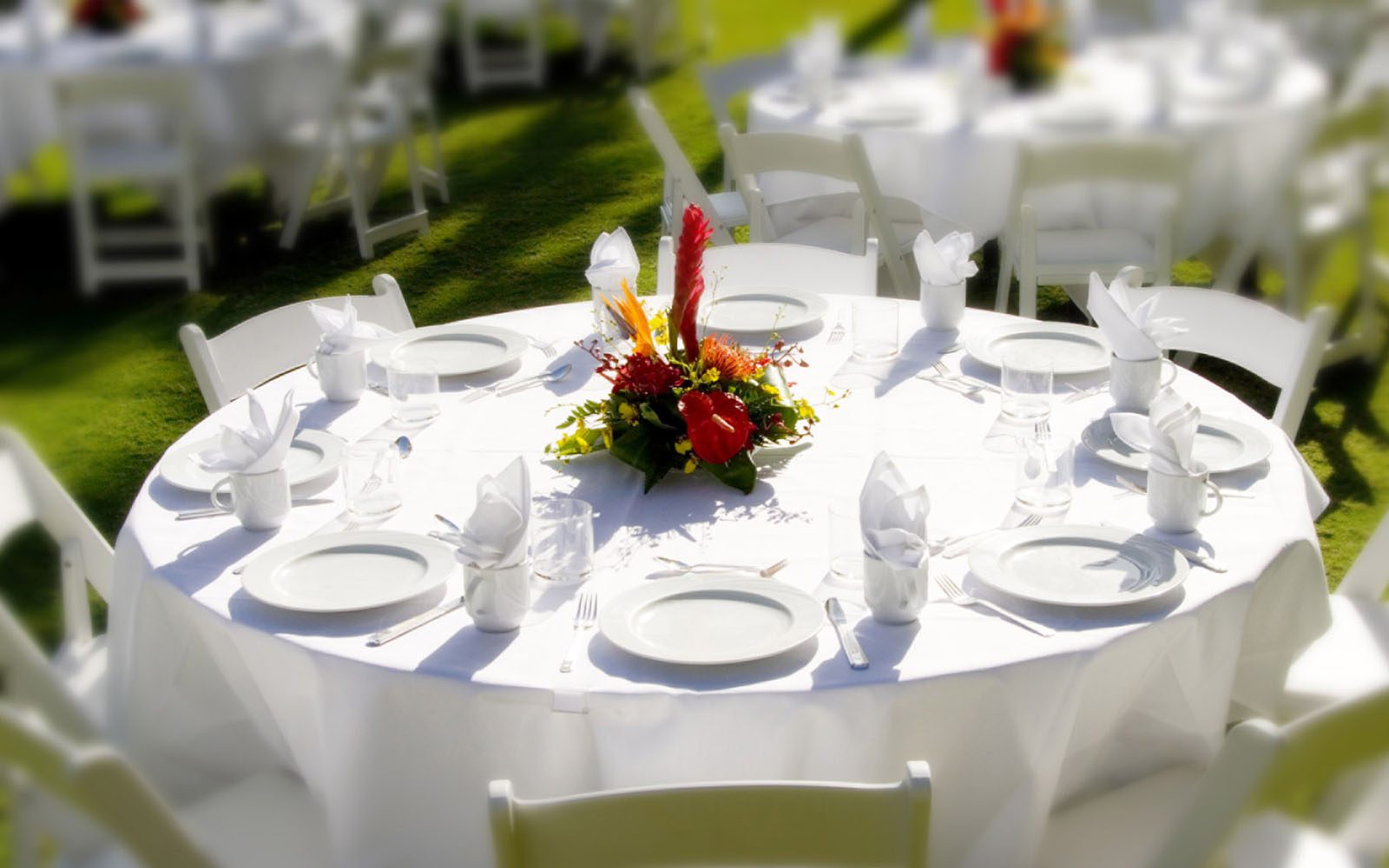 White tablecloth and plates on a round table set for an event on a lawn at Hilton Hawaiian Village