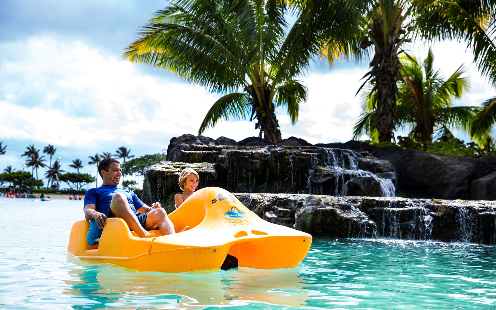 Father and son riding in a water vehicle on the Duke Kahanamoku Lagoon