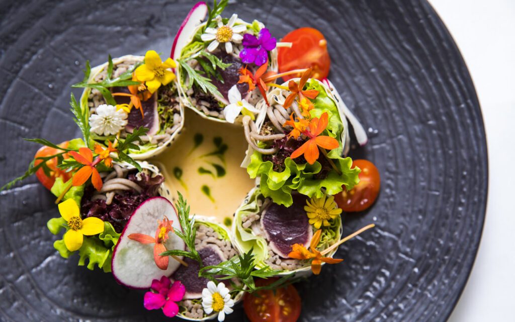 Colorful sushi style dish topped with edible flowers