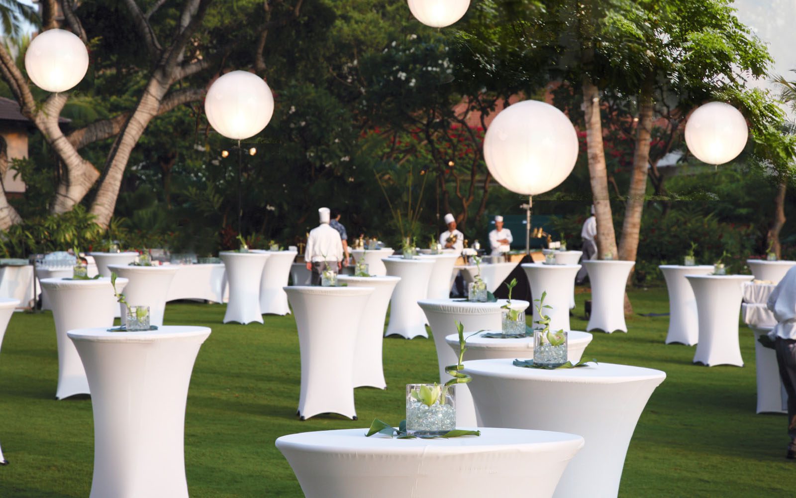 White high tables set up on the Great Lawn with Chefs in Hats and white ball lights hanging from the trees