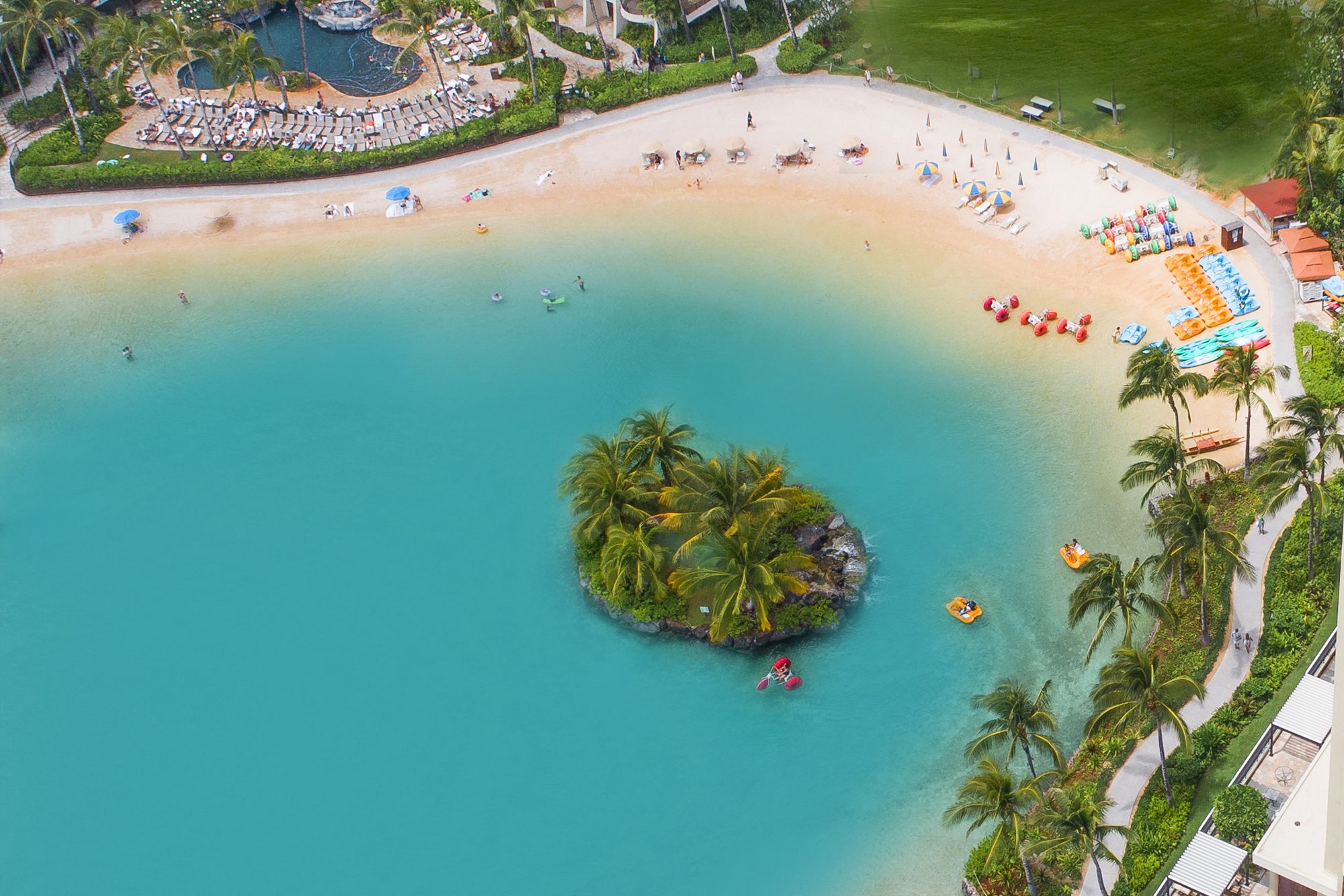 Aerial view of Duke Kahanamoku Lagoon with island in the center and watercraft in and around the lagoon.
